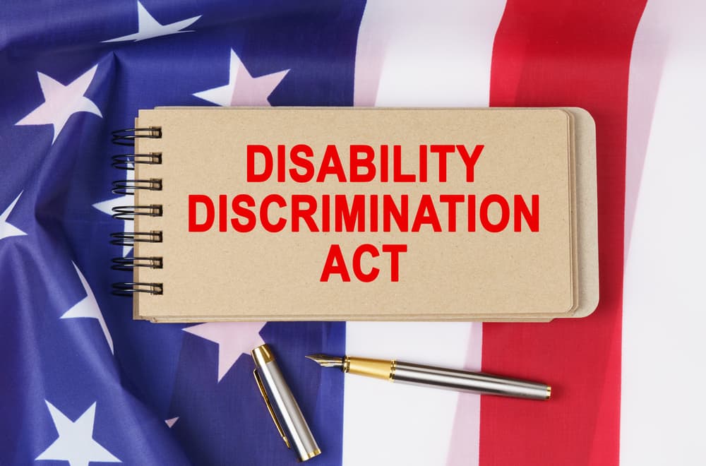Concept of law and order: A notebook labeled "DISABILITY DISCRIMINATION ACT" rests on the backdrop of the United States flag.