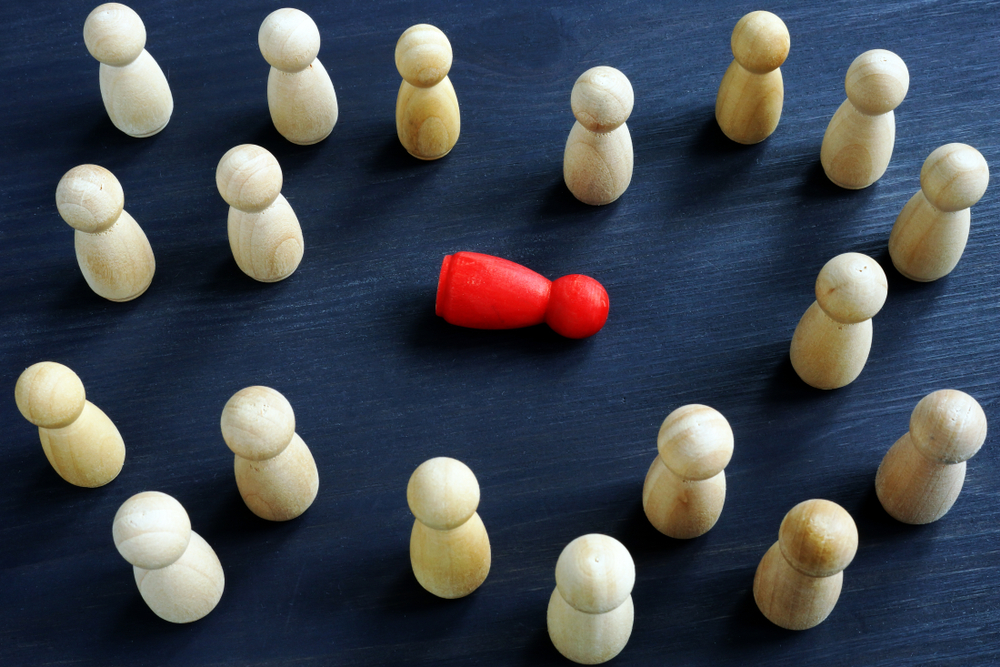 Wooden figurines on a desk symbolizing workplace bullying, harassment, and loneliness