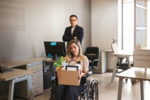 Sad looking disabled woman carrying her personal belongings while being fired from her job