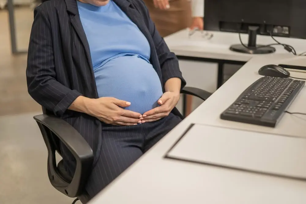 Close-up of belly of pregnant woman working in office.