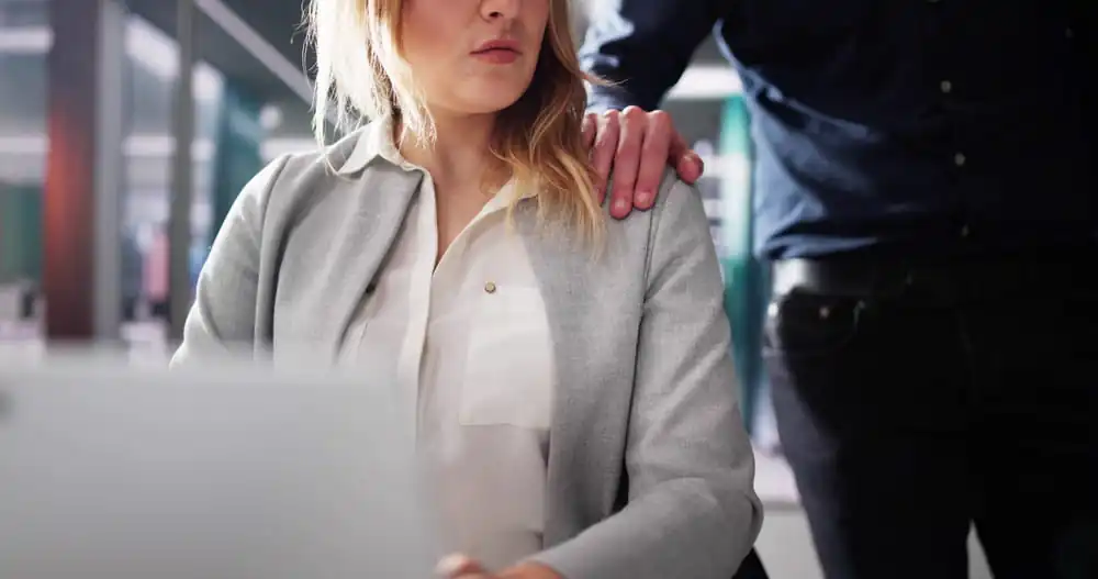Supervisor placing hand on employee’s shoulder in uncomfortable workplace situation illustrating quid pro quo harassment