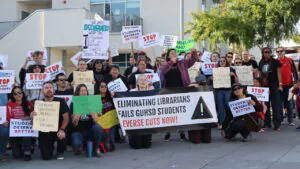 Grossmont Union High School District teachers and community members protest librarian layoffs, holding signs reading "Students Deserve Better" and "Eliminating Librarians Fails GUHSD Students."