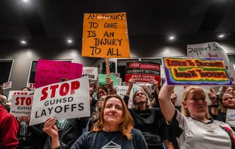 People hold signs during the Grossmont Union High School District board meeting on April 24, 2025 in Grossmont. / Ariana Drehsler for Voice of San Diego